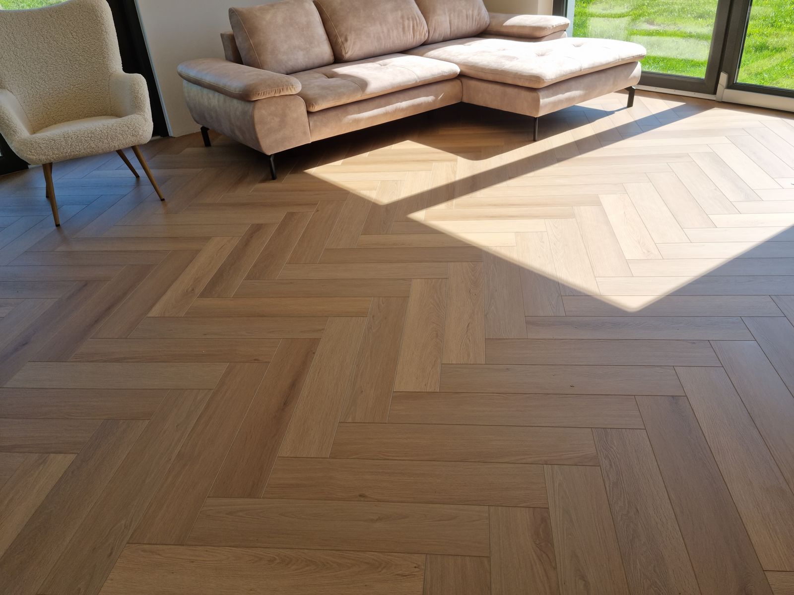 Panele winylowe w jodełkę w salonie z narożnikiem i dużym oknem – realizacja Perfekt Parkiet