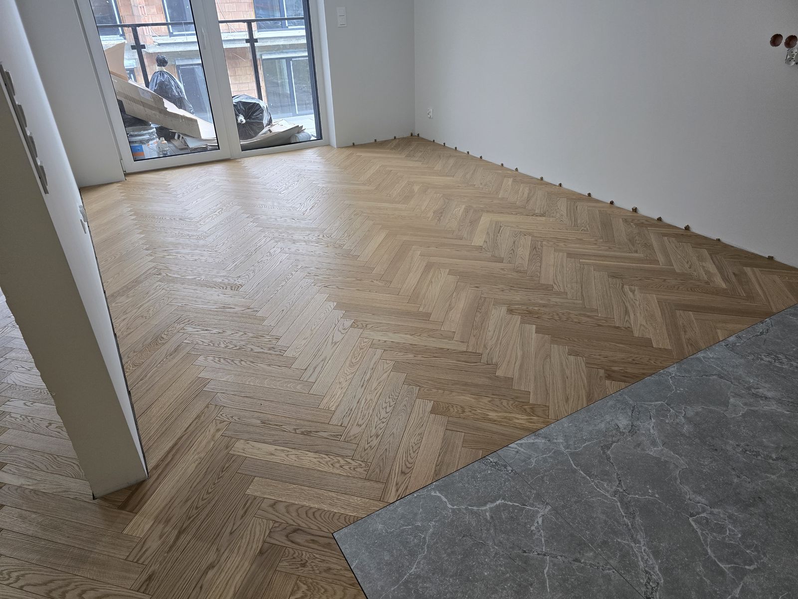 Dębowa jodełka docięta do płytek w korytarzu mieszkania – realizacja Perfekt Parkiet